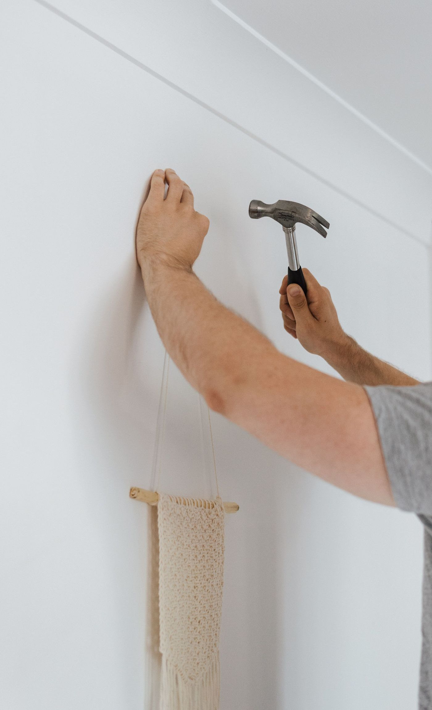 Side view of bearded craftsman with hammer putting decoration on wall during renovation works
