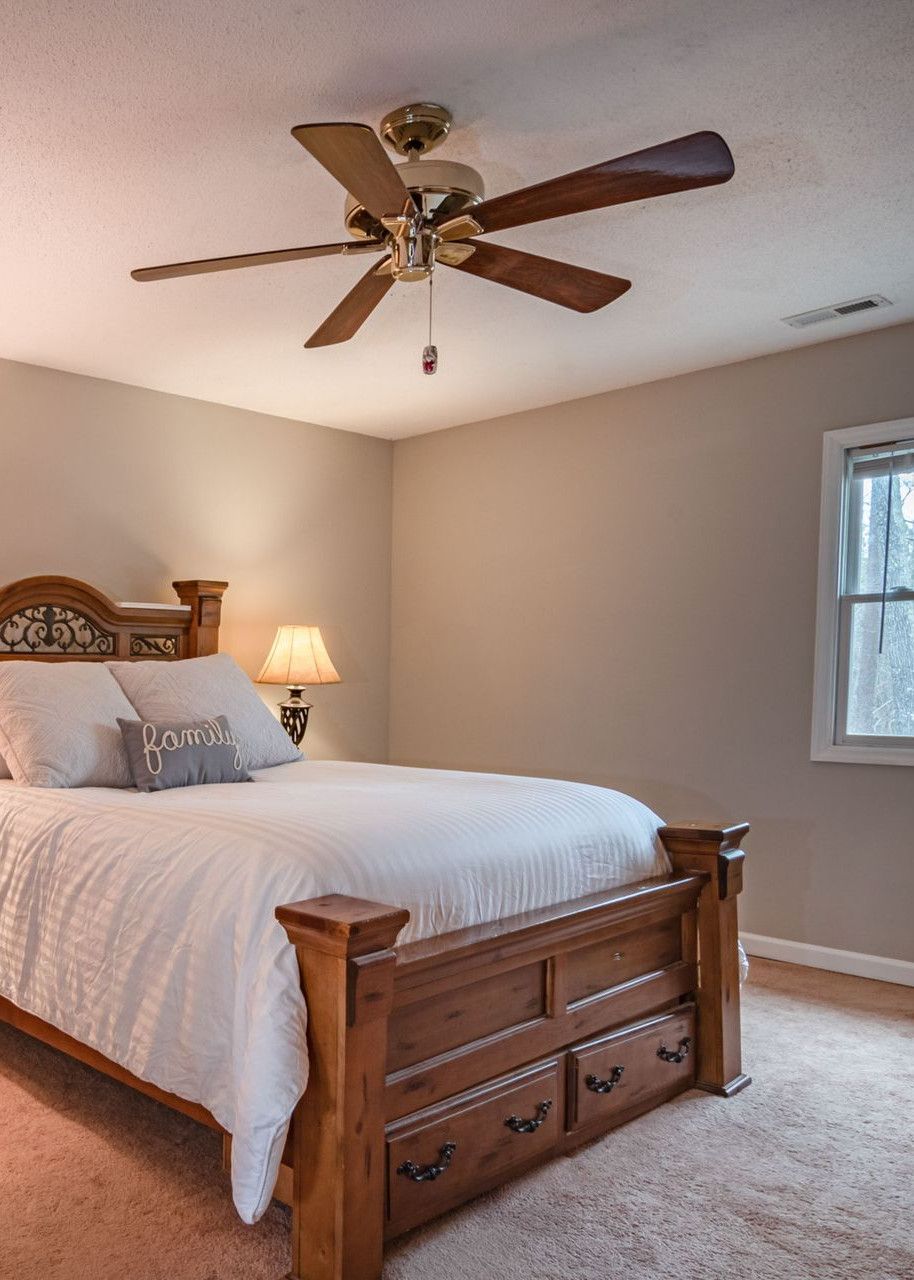 Warm and inviting bedroom featuring a wooden bed, ceiling fan, and cozy decor.